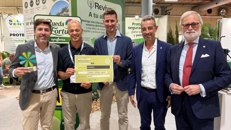Cinco hombres en un stand, uno sostiene diploma y otro el premio interflora