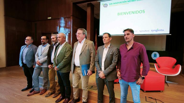 Grupo de hombres en un escenario durante un evento, con pantalla de bienvenida al fondo.