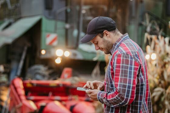 Syngenta | imagen  | imagen de un hombre en campo mirando un móvil, con cosechadora por detrás